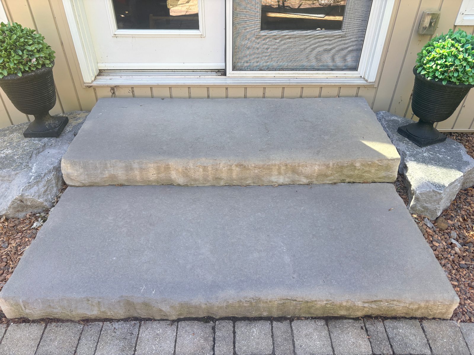 Natural stone slab steps at a front entrance with planted urns